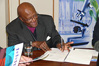 Desmond Tutu signs the agreement